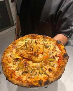 Die Meeresfrüchte-Pizza ist eine Liebeserklärung an mediterrane Aromen, Holzofen gebacken